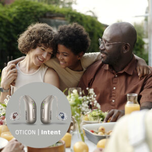 A family laughing at brunch. The older man is wearing an oticon hearing aid.